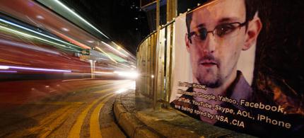 A bus drives past a banner supporting Edward Snowden in Hong Kong's business district, 06/17/13.  (photo: Kin Cheung/AP)