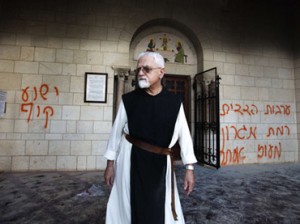 Trappist monk walks past graffiti that reads 'Jesus monkey' in Hebrew sprayed on the walls of the Latrun monastry